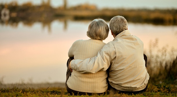 elderly couple sat down near lake
