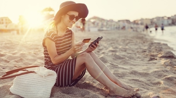 Woman at the beach using credit card for online shopping 